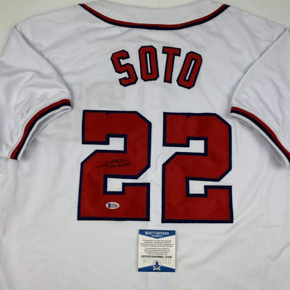 Back of a white custom baseball jersey with red and navy blue soto 22 lettering signed by juan soto from professional sports league