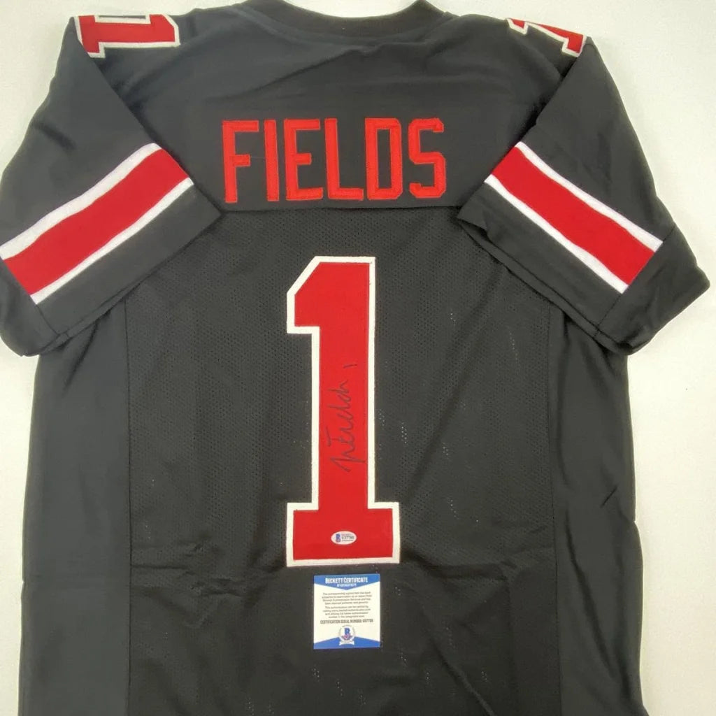 Back of autographed justin fields ohio state black custom jersey with red and white trim from professional sports league