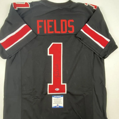 Back of autographed justin fields ohio state black custom jersey with red and white trim from professional sports league