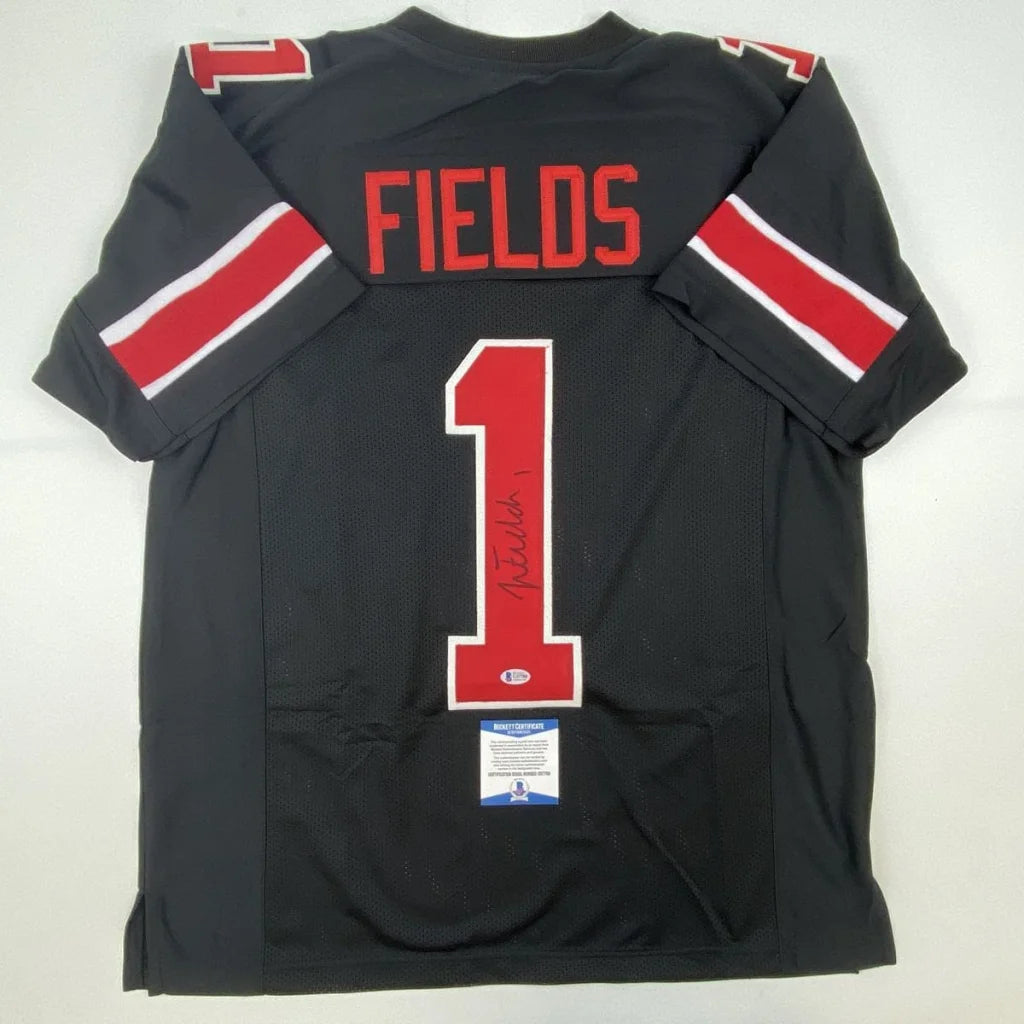 Back of a black ohio state custom jersey with red and white lettering signed by professional sports player justin fields