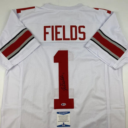 Back side of autographed white ohio state college football custom jersey with red and black striped sleeves by justin fields
