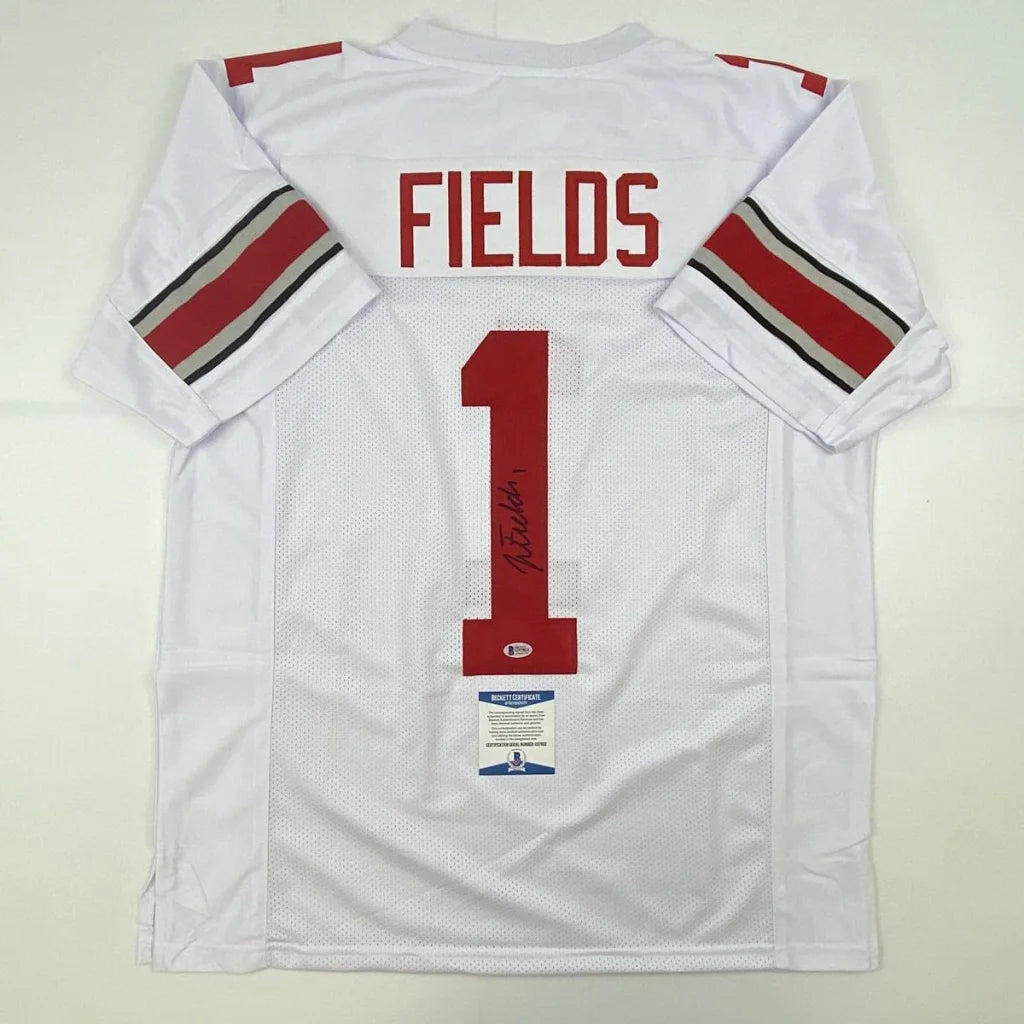 Back of autographed white Ohio State Buckeyes custom jersey with red and gray sleeve stripes featuring Fields 1