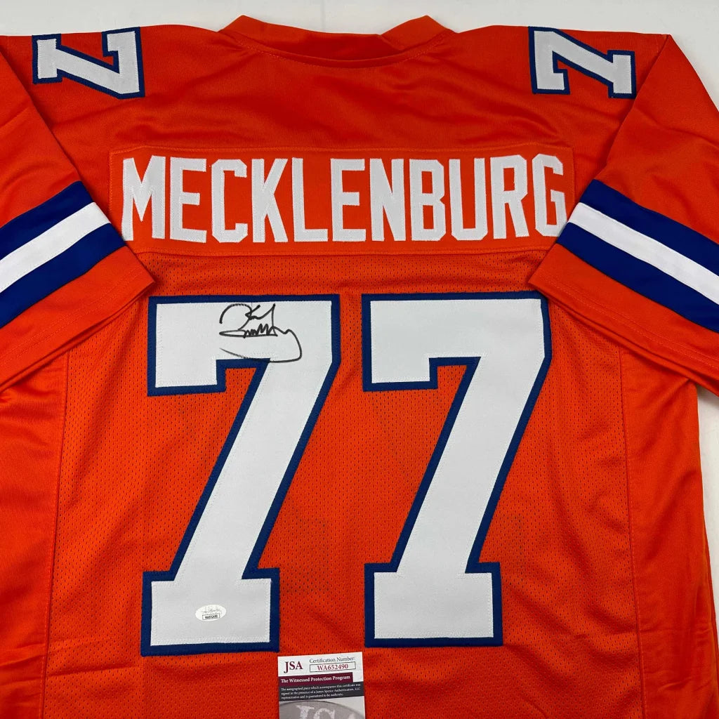 Back of an autographed karl mecklenburg denver orange football custom jersey with white and blue trim number 77 professional sports league