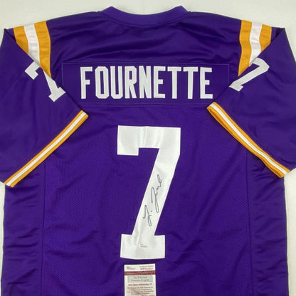Back of an autographed purple louisiana state university custom jersey with white and gold trim featuring fournette 7 from a professional sports league