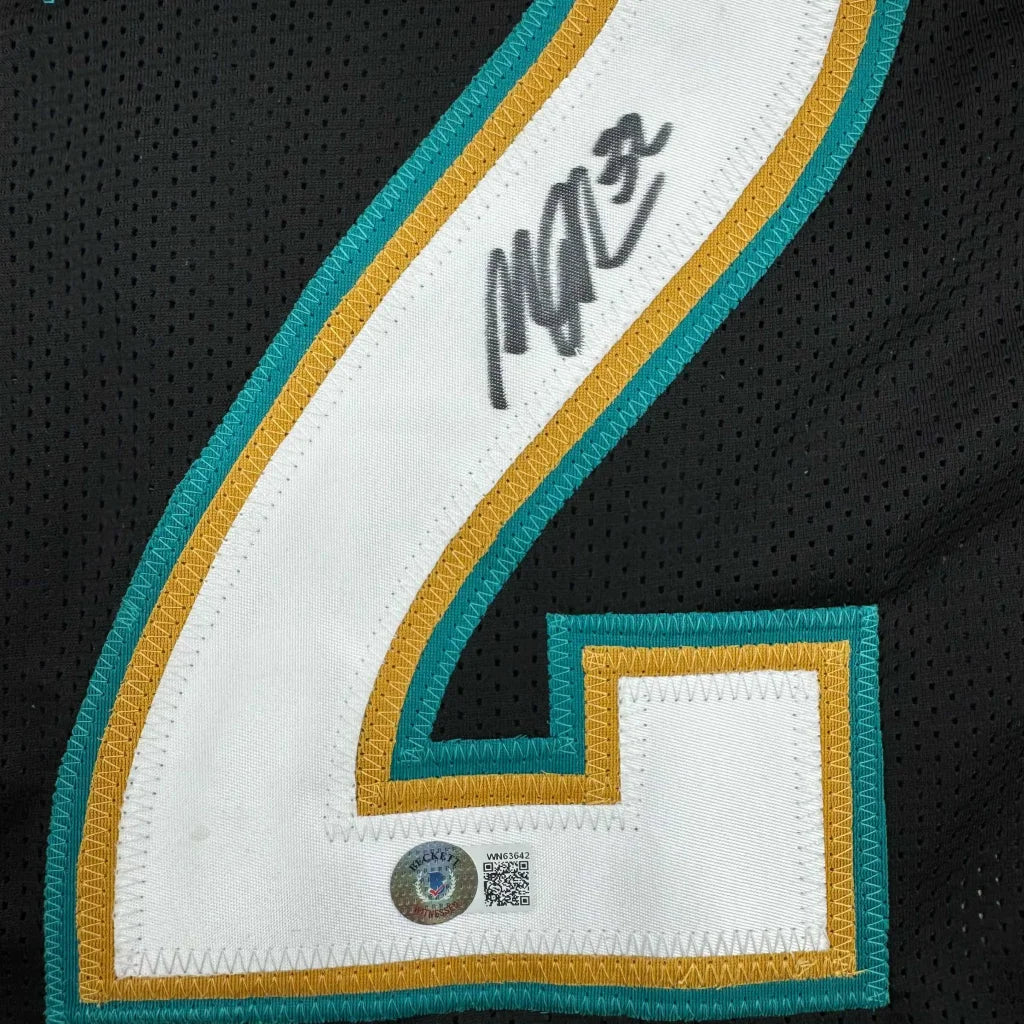Black custom jersey with teal and gold number 4 and signature from a pro sports league