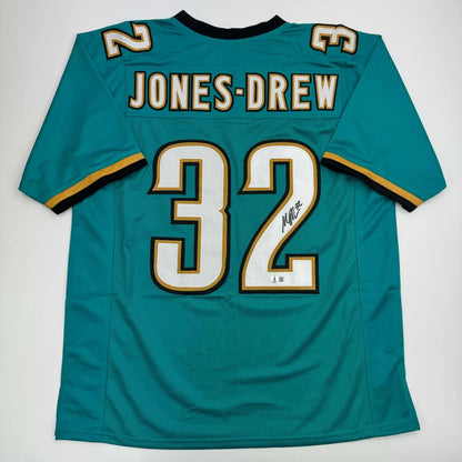 Autographed teal professional sports league jersey with white and gold numbers and letters