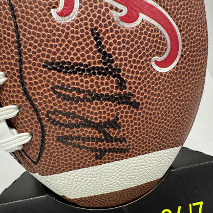 Brown leather football with black laces, red and white emblem on display stand