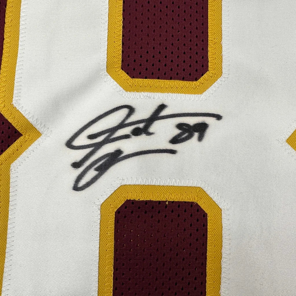 Autographed white and maroon football custom jersey with gold trim featuring black autograph for professional sports league fans