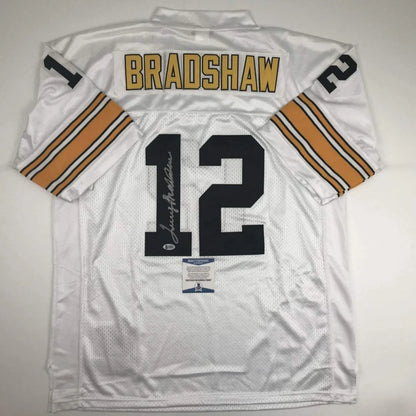 Back view of autographed professional sports white football jersey with gold and black bradshaw 12 lettering