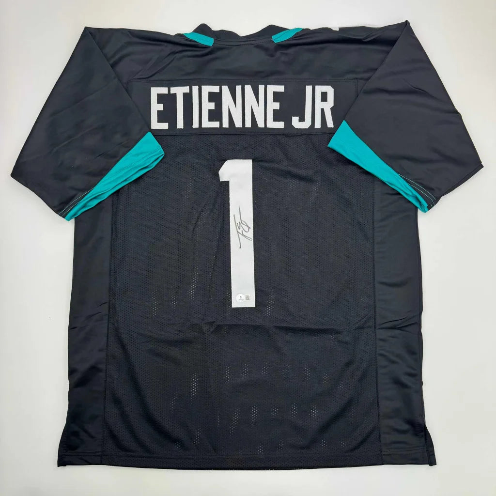 Autographed Travis Etienne Jr. black custom jersey with teal accents, number 1