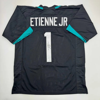 Autographed Travis Etienne Jr. black custom jersey with teal accents, number 1