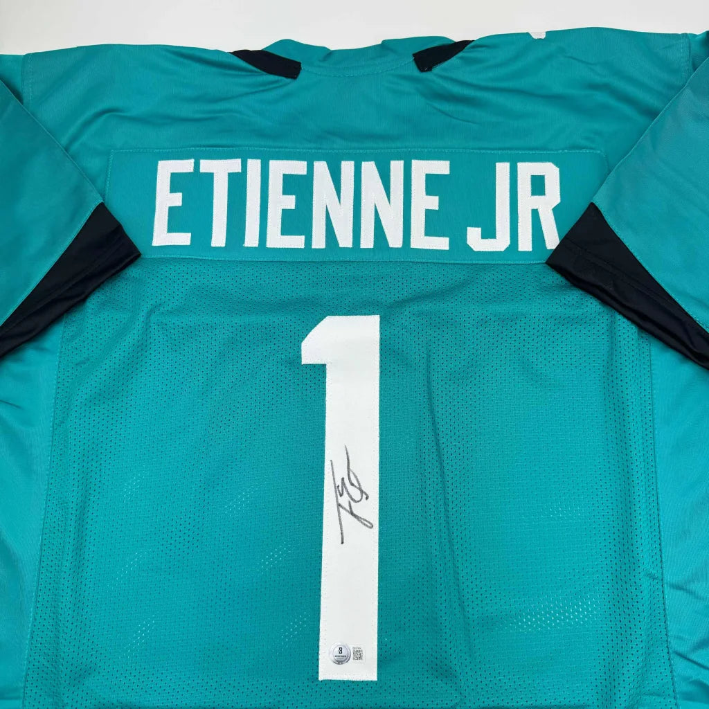 Teal professional sports league jersey signed by Etienne Jr with white ETIENNE JR and 1