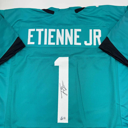 Teal professional sports league jersey signed by Etienne Jr with white ETIENNE JR and 1