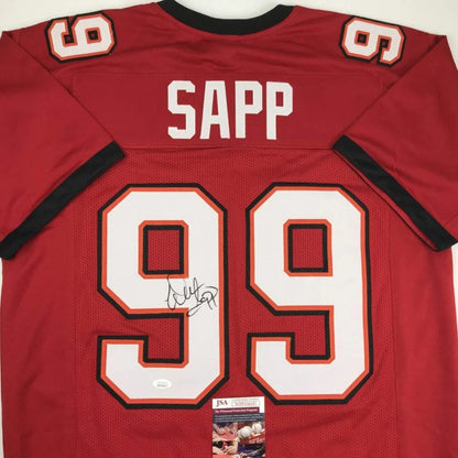 Back of a red tampa bay buccaneers custom jersey featuring white and black numerals with sapp 99 autograph from professional sports league