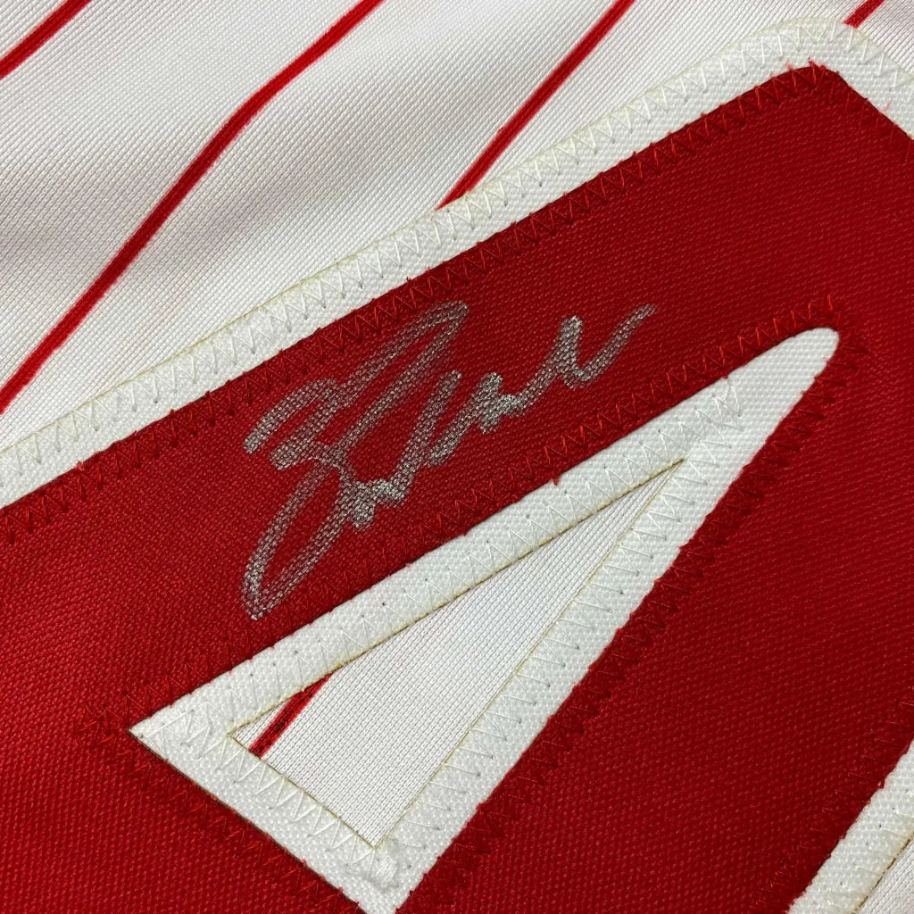 White professional sports league jersey with red pinstripes, number 4, and silver autograph