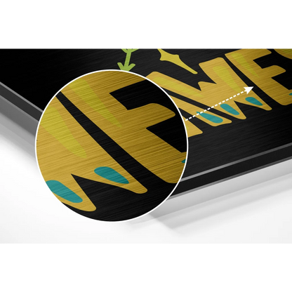 Black framed brushed aluminium dibond art with bold gold lettering and teal accents