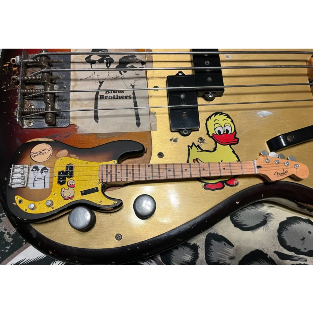 Axe Heaven Fender mini guitar with Blues Brothers decals on adjustable A-frame stand