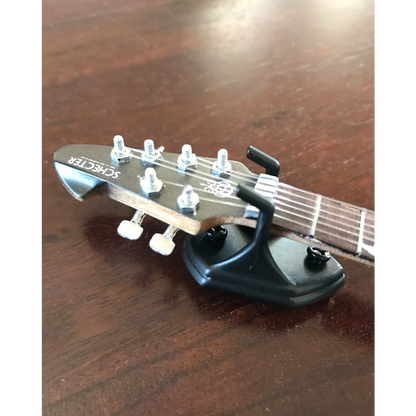 Axe Heaven black Schecter guitar capo with white strings in wall hangers