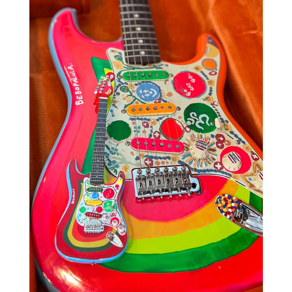 Axe Heaven mini guitar Rocky Strat in 1960s psychedelic rainbow hues with adjustable A-frame stand