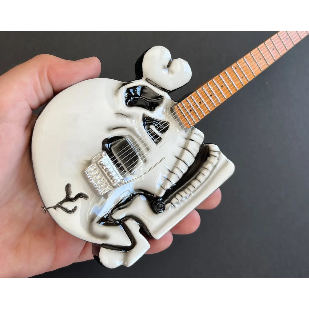 Skull-shaped Axe Heaven miniature guitar replica on adjustable A-frame stand