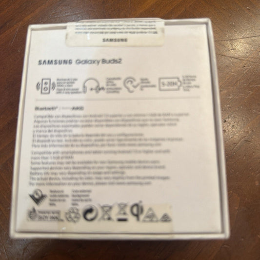 Back of Samsung Galaxy Buds 2 white packaging box showing product specifications, features, and regulatory information on wooden surface.