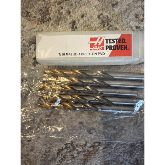 Haas 7/16 M42 jobber drill bits with gold TiN coating in plastic packaging labeled "Tested. Proven." on concrete surface.