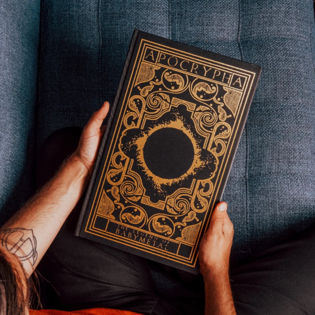 Black hardcover babymetal deluxe edition book apocrypha with intricate gold foil detailing by gmb chomichuk 9x15