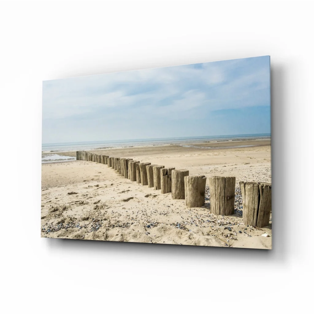 Beige wooden beach breakwater posts in glass wall art print