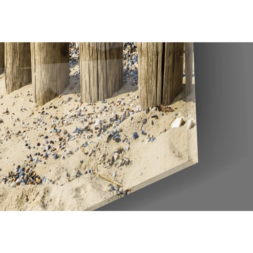Weathered wooden pilings on sandy beach in coastal glass wall art print