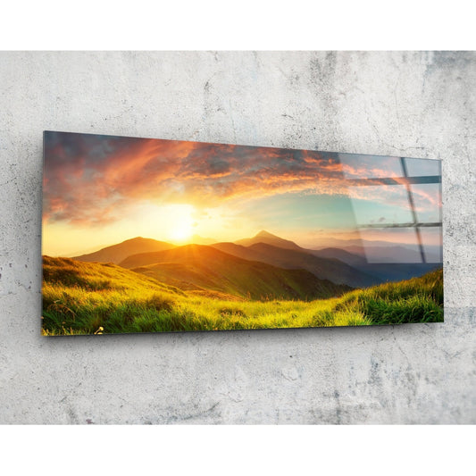 Rectangular glass wall panel mounted on concrete showing golden sunset over green mountain valley with orange sky.