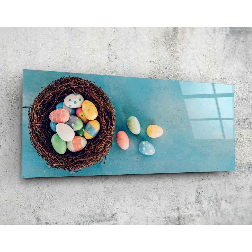 Overhead view of turquoise glass wall art displaying a woven nest filled with colorful painted eggs and scattered eggs on the surface.