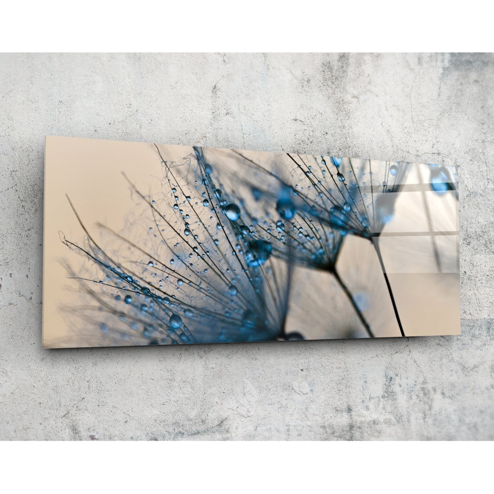 Multi-panel glass wall art displaying a close-up dandelion with blue water droplets against a beige background, mounted on concrete.