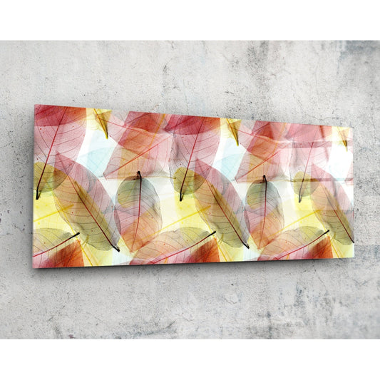 Rectangular glass wall art panel displaying translucent autumn leaves in red, orange, and yellow tones on white background, photographed flat against concrete.
