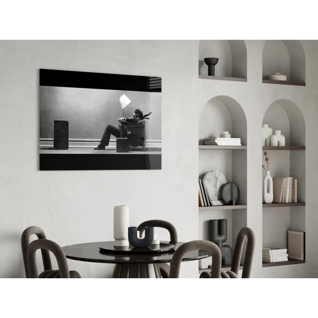 Striking black and white wall art of person reclining in armchair under lamp