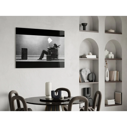 Striking black and white wall art of person reclining in armchair under lamp