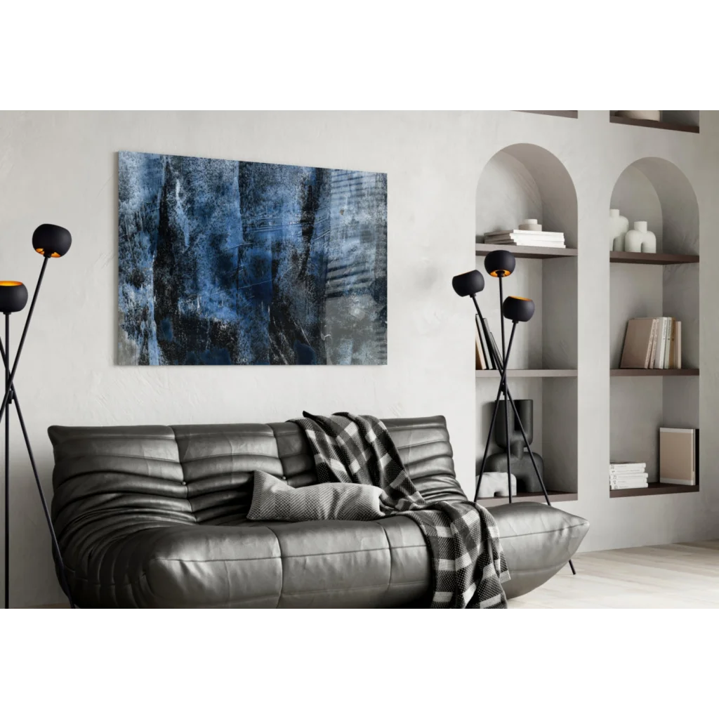 Sleek gray leather sofa with plaid throw under Deep Blue Abstract wall art