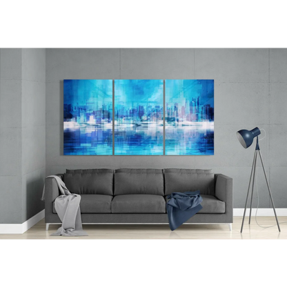 Blue abstract cityscape glass wall art triptych above gray sofa