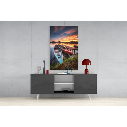 Vibrant lakeside sunset glass wall art with red and blue canoes on dock