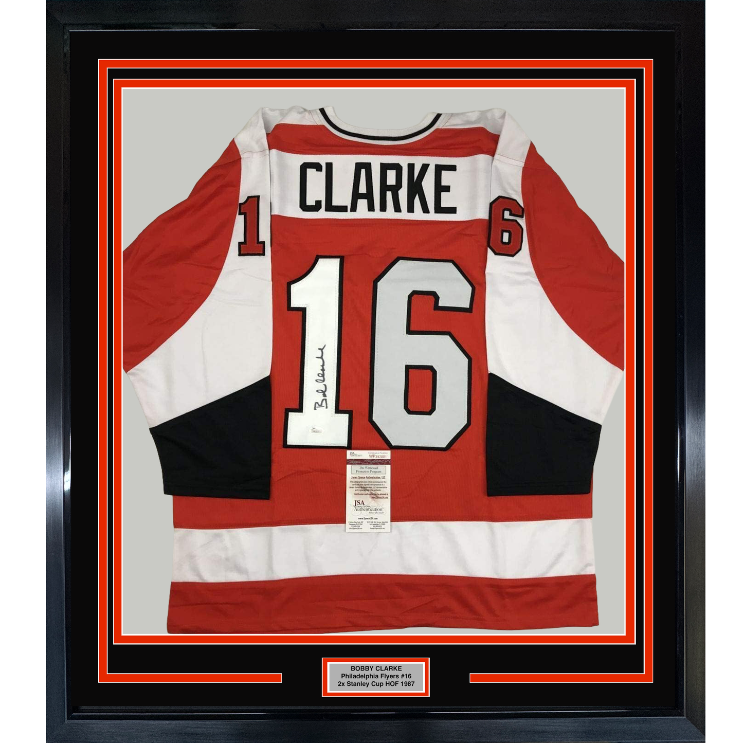 Framed Philadelphia Flyers red, white, and black hockey jersey number 16 signed by Bobby Clarke with JSA authentication certificate visible.