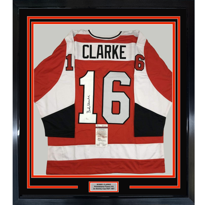 Framed Philadelphia Flyers red, white, and black hockey jersey number 16 signed by Bobby Clarke with JSA authentication certificate visible.