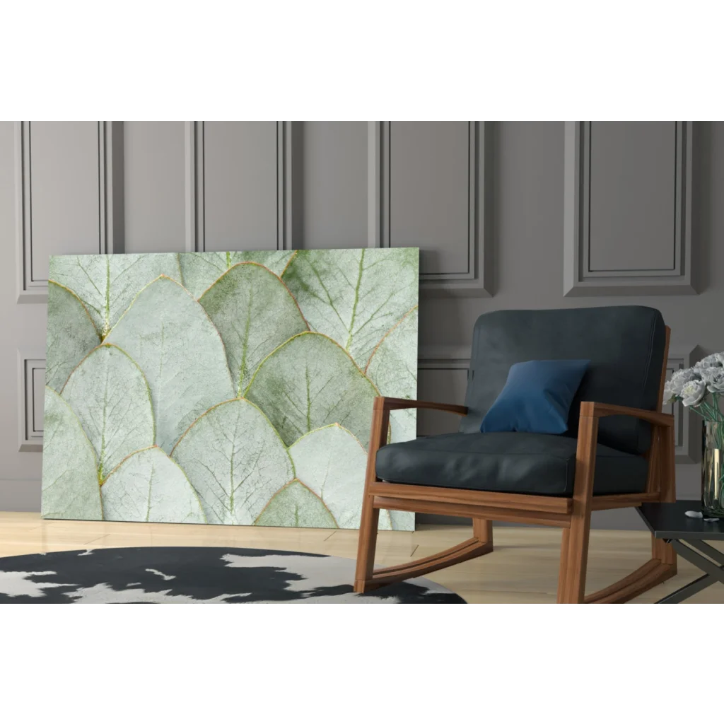 Modern glass wall art with overlapping light green leaves and gold veining on gray wall