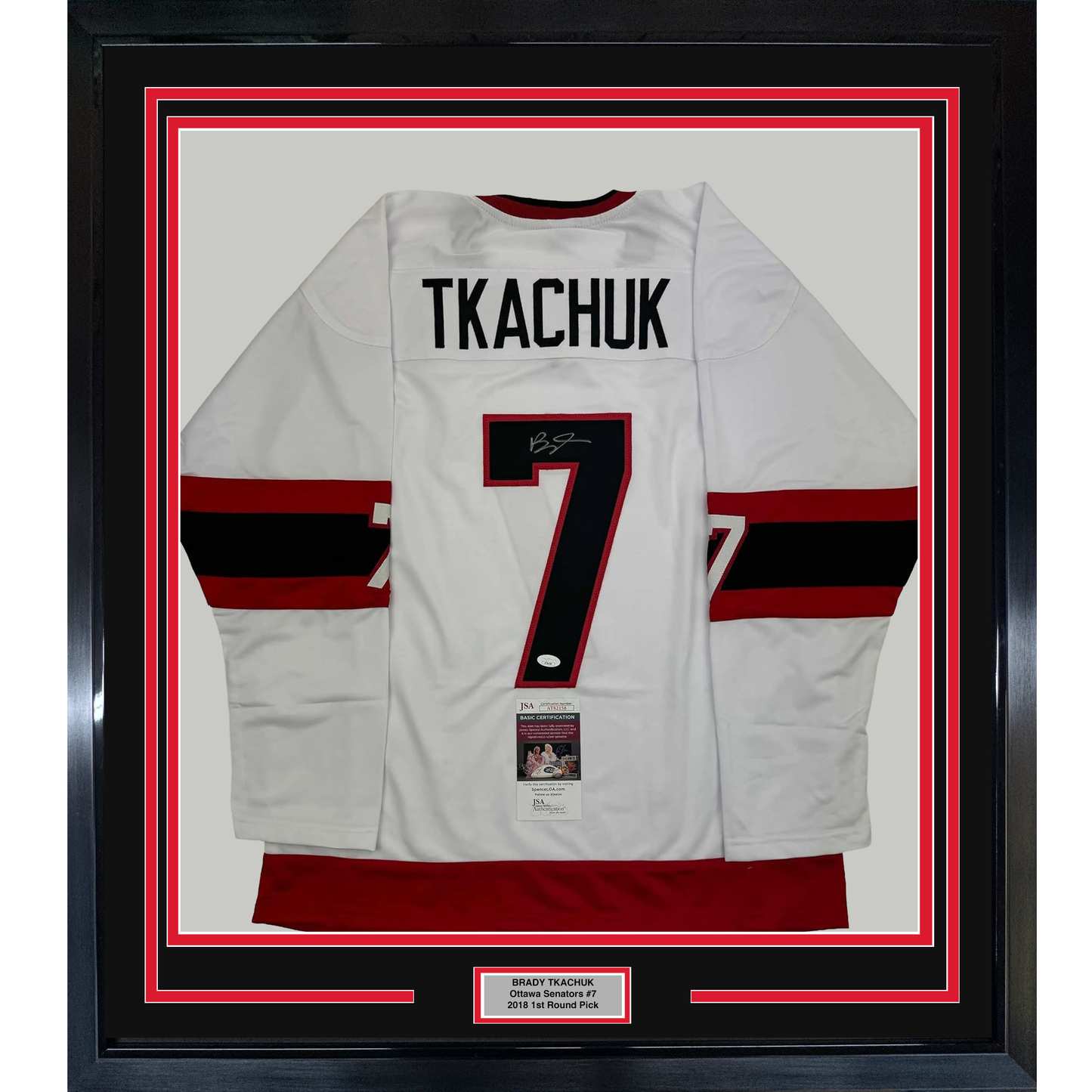 Framed white hockey jersey with red and black stripes, number 7, and "TKACHUK" nameplate, displayed flat against red and black matting with JSA certification label visible.