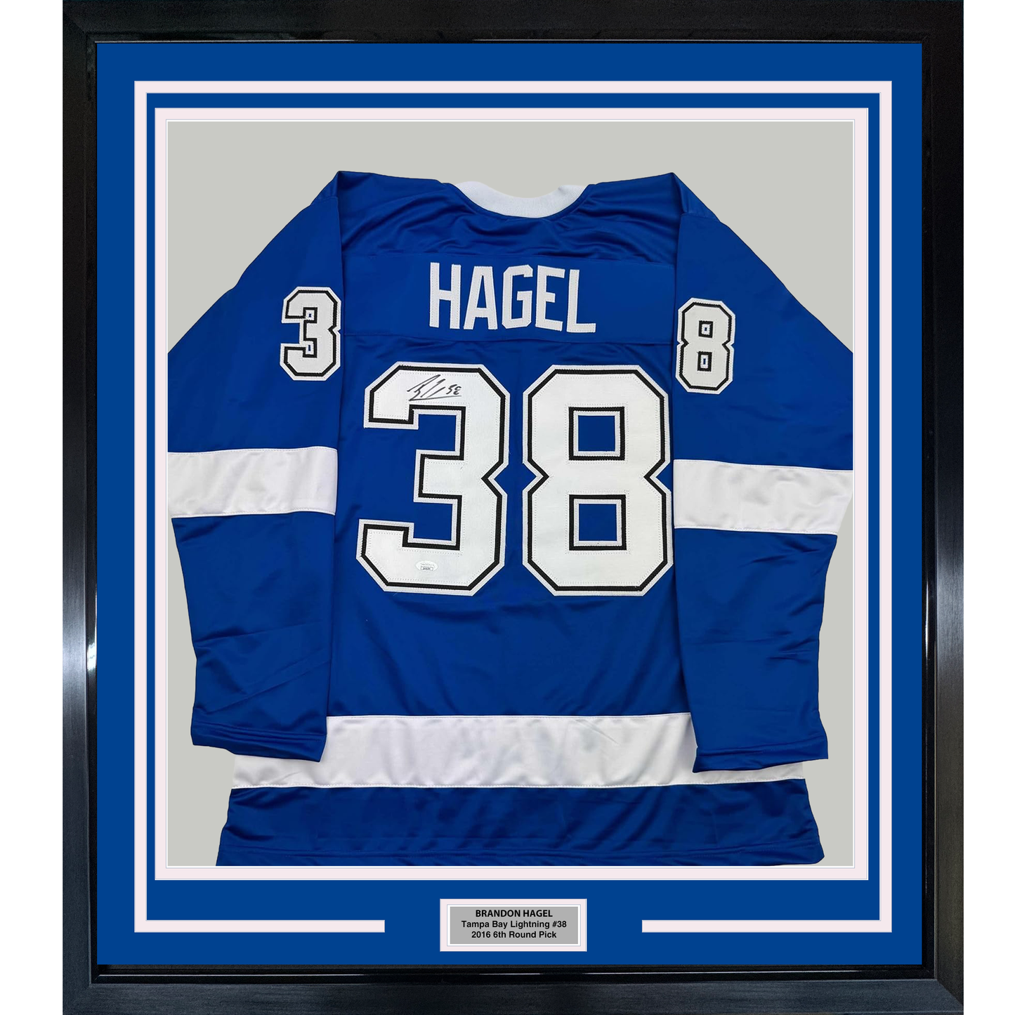 Framed blue and white striped hockey jersey displaying "HAGEL" and number 38 with signature, mounted flat against gray backing with nameplate below.