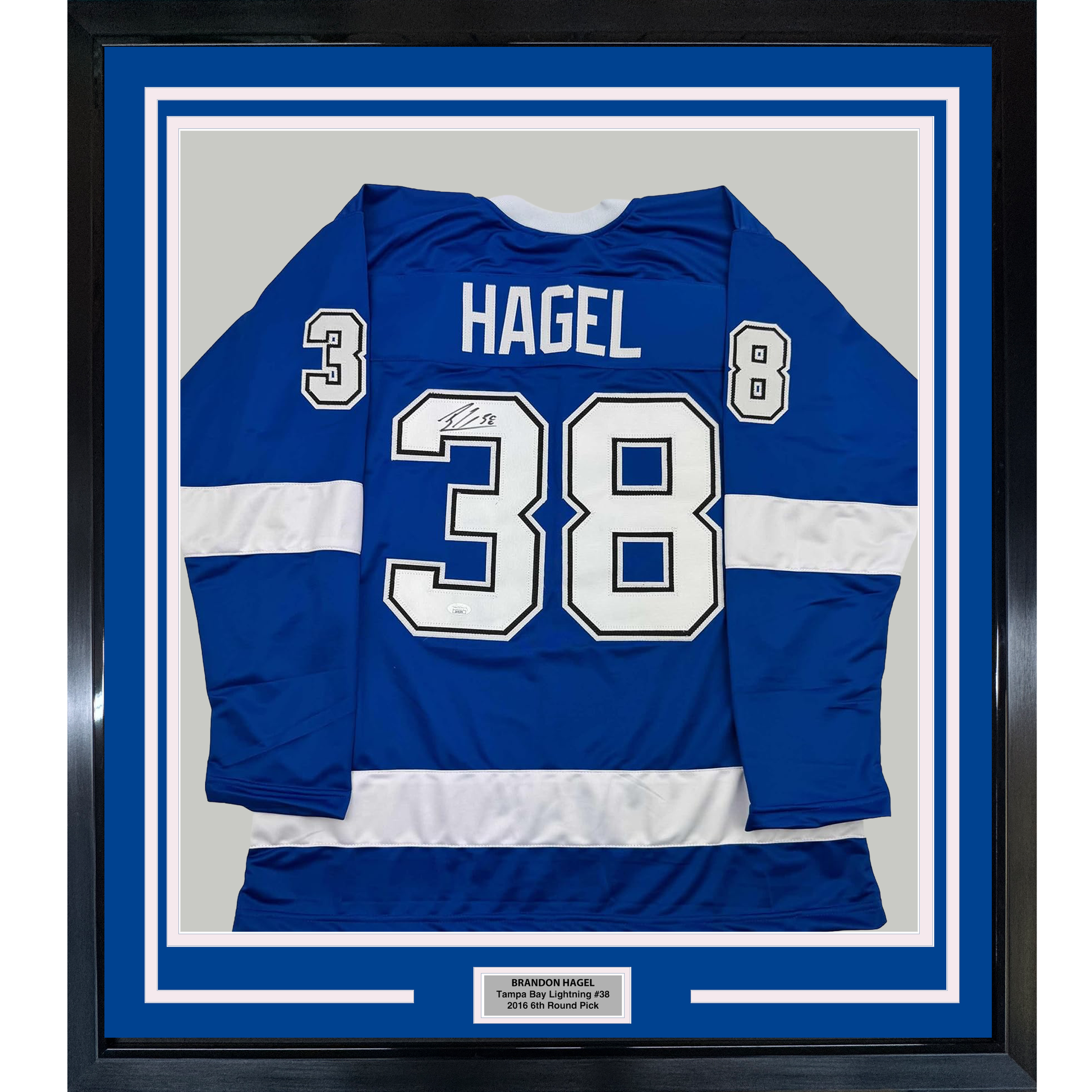 Framed blue and white striped hockey jersey displaying "HAGEL" and number 38 with signature, mounted flat against gray backing with nameplate below.