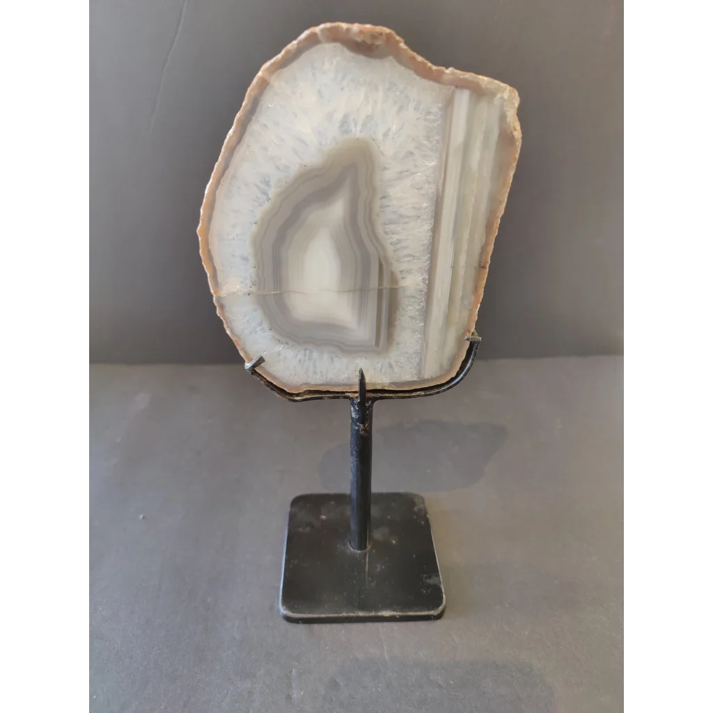 Polished Brazilian agate slice with white gray bands on metal display stand