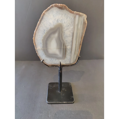 Polished Brazilian agate slice with white gray bands on metal display stand