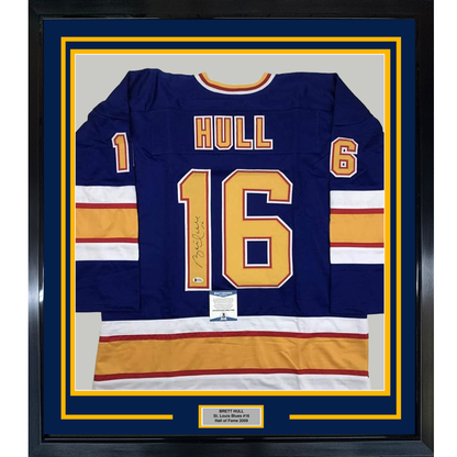 Framed navy St. Louis Blues hockey jersey number 16 with "HULL" printed across chest, gold and white stripes on sleeves, signed in gold pen.