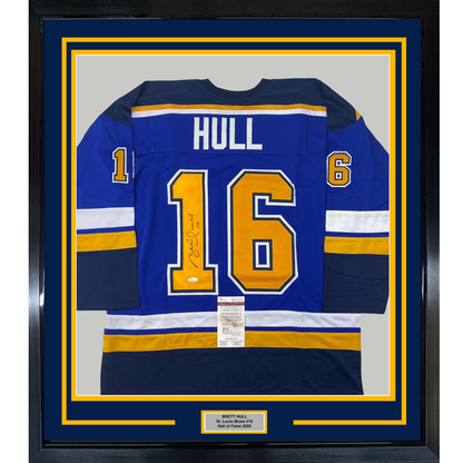 Framed blue St. Louis Blues hockey jersey number 16 with "HULL" nameplate and autograph, displayed front-facing with yellow and white stripes.