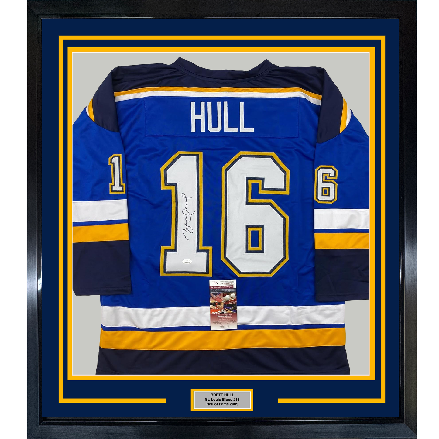 Framed Brett Hull autographed St. Louis Blues #16 blue hockey jersey with yellow and white trim, displayed front-facing with nameplate below.
