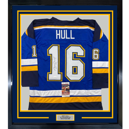 Framed Brett Hull autographed St. Louis Blues #16 blue hockey jersey with yellow and white trim, displayed front-facing with nameplate below.
